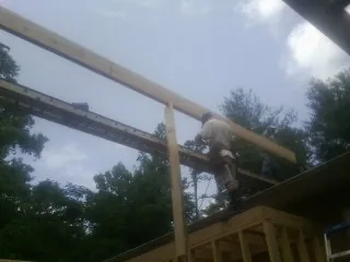 Carpenter setting a ridge beam over a new addition frame — Ice Dam Removal by Roofing Brothers in Charlottesville