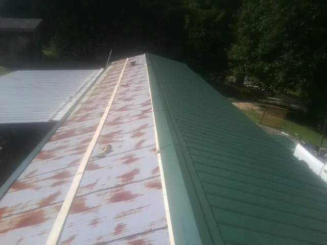 Old rusted panels beside newly installed green metal roofing — Wind Damage Roof Repair by Roofing Brothers in Charlottesville