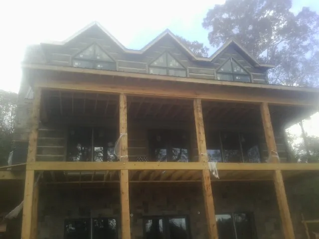 Dormers and porch framing on a large log home under construction — Roof Coating work by our crew in Charlottesville