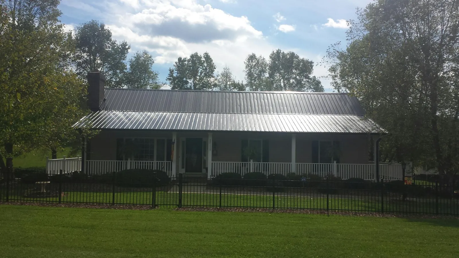 Gray metal roof on a brick ranch with a full width front porch — Gutter Guard Installation work by our crew in Charlottesville