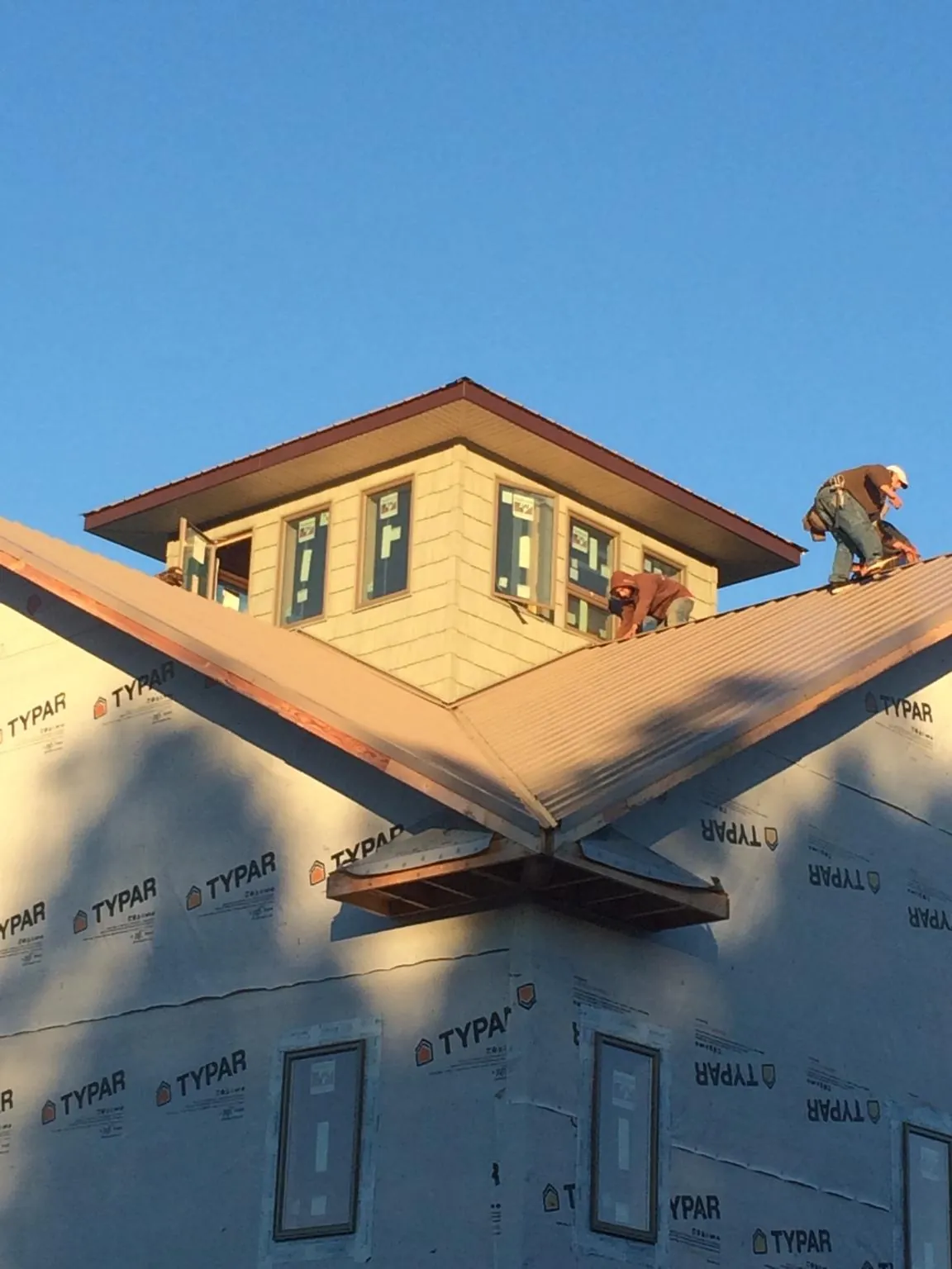 Roofers working around a rooftop cupola on a new metal roof at sunset — Roof Waterproofing in Charlottesville by Roofing Brothers